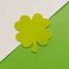 A simple, minimalist four leaf clover design on a green and white background, perfect for festive themes.